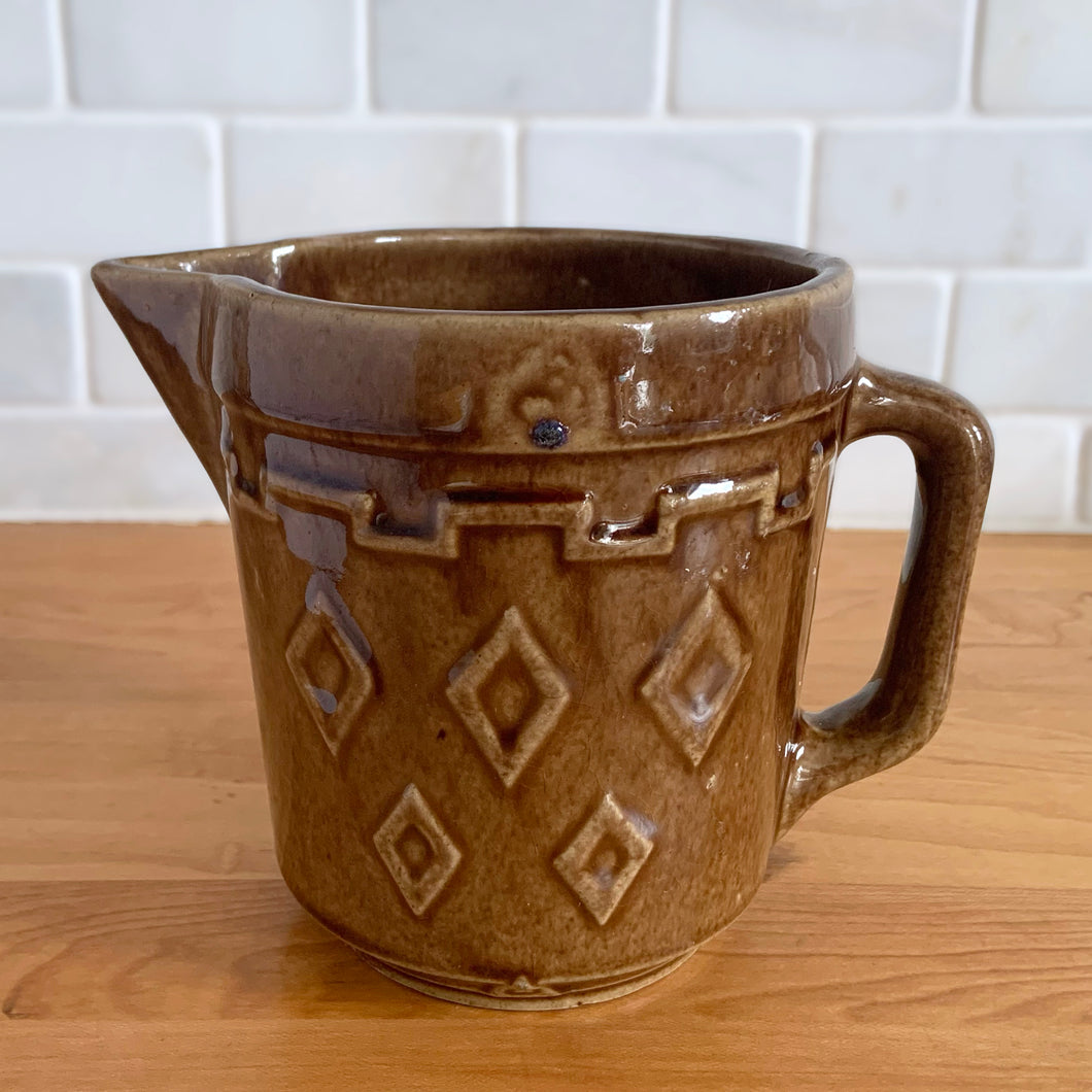 Vintage glossy caramel brown stoneware pitcher featuring a castle turret with diamonds detail. Crafted by Monmouth Western Stoneware, USA, 1920s. Add this utilitarian piece to your farmhouse decor or art pottery collection!

In excellent condition, no chips/cracks/repairs, age-related crazing. Unmarked.

Measures 4 1/2 x 5 inches