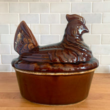 Load image into Gallery viewer, Vintage brown drip glaze hen-on-nest oven-proof casserole dish. Crafted by Hull Pottery, USA, 1960s. What a fabulous way to prepare and serve your favourite casserole!

In excellent condition, no chips/cracks/repairs. Maker's marks.

Measures 10 x 7 1/2 x 9 3/4 inches
