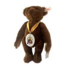 Load image into Gallery viewer, Vintage 150th Anniversary bear is made brown mohair. Brown hand embroidered nose and claws, brown glass eyes with black pupils, and light beige felt hand and foot pads. Flat foot pads enable it stand. Has a squeaker and is fully jointed. Gold satin ribbon with porcelain medallion displays a picture of Margarete Steiff. Brass button-in-ear red and white tag, and two paper tags. A must-have for any Steiff or teddy bear collector! In excellent condition. Measures 11 inches or 28cm tall
