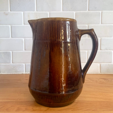 Vintage gloss brown stoneware pitcher with ribbed bands. Crafted by Medalta Stoneware, Canada, 1924. This utilitarian piece nicely complement any farmhouse or cottage kitchen!

In as found vintage condition, no chips/repairs, 3 hairline cracks, age-related wear to the exterior. Unmarked.

Measures 6 3/8 x 7 1/4 inches