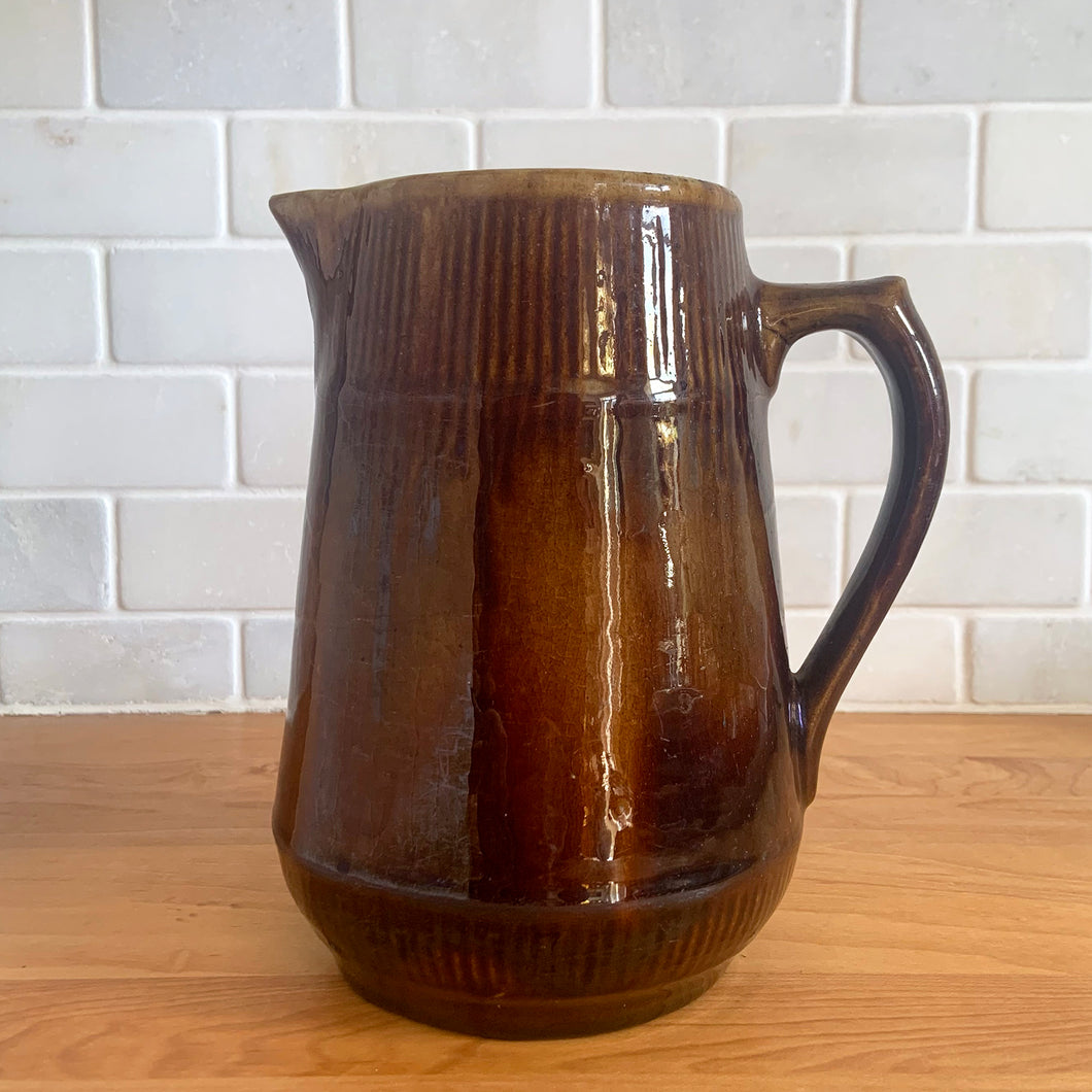 Vintage gloss brown stoneware pitcher with ribbed bands. Crafted by Medalta Stoneware, Canada, 1924. This utilitarian piece nicely complement any farmhouse or cottage kitchen!

In as found vintage condition, no chips/repairs, 3 hairline cracks, age-related wear to the exterior. Unmarked.

Measures 6 3/8 x 7 1/4 inches