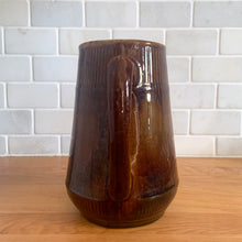 Load image into Gallery viewer, Vintage gloss brown stoneware pitcher with ribbed bands. Crafted by Medalta Stoneware, Canada, 1924. This utilitarian piece nicely complement any farmhouse or cottage kitchen!

In as found vintage condition, no chips/repairs, 3 hairline cracks, age-related wear to the exterior. Unmarked.

Measures 6 3/8 x 7 1/4 inches
