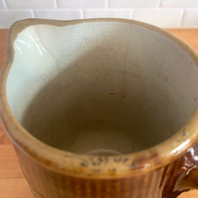 Load image into Gallery viewer, Vintage gloss brown stoneware pitcher with ribbed bands. Crafted by Medalta Stoneware, Canada, 1924. This utilitarian piece nicely complement any farmhouse or cottage kitchen!

In as found vintage condition, no chips/repairs, 3 hairline cracks, age-related wear to the exterior. Unmarked.

Measures 6 3/8 x 7 1/4 inches
