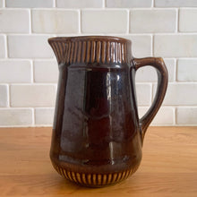 Load image into Gallery viewer, Vintage gloss brown stoneware pitcher with ribbed bands. Crafted by Medalta Stoneware, Canada, 1924. This utilitarian piece nicely complement any farmhouse or cottage kitchen!

In good vintage condition, no chips/cracks/repairs, age-related wear to the exterior. Unmarked.

Measures 5 x 5 1/2 inches
