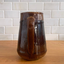 Load image into Gallery viewer, Vintage gloss brown stoneware pitcher with ribbed bands. Crafted by Medalta Stoneware, Canada, 1924. This utilitarian piece nicely complement any farmhouse or cottage kitchen!

In good vintage condition, no chips/cracks/repairs, age-related wear to the exterior. Unmarked.

Measures 5 x 5 1/2 inches
