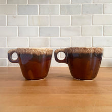 Load image into Gallery viewer, Pair of vintage glossy brown drip glaze mugs. Crafted by Hull Pottery, USA, 1960s. Enjoy any hot beverage in this fabulous retro oven-proof tableware!

In excellent condition, no chips/cracks/repairs. Maker&#39;s marks.

Measures 3 5/8 x 3 1/8 inches

Capacity 8 ounces
