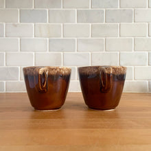 Load image into Gallery viewer, Pair of vintage glossy brown drip glaze mugs. Crafted by Hull Pottery, USA, 1960s. Enjoy any hot beverage in this fabulous retro oven-proof tableware!

In excellent condition, no chips/cracks/repairs. Maker&#39;s marks.

Measures 3 5/8 x 3 1/8 inches

Capacity 8 ounces
