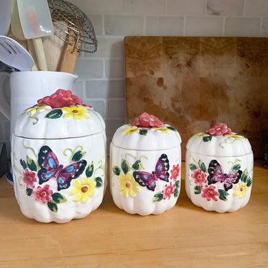 Rare set of three vintage mid-century white figural pumpkin/squash ceramic canisters. These three dimensional beauties are hand painted with colourful butterflies and flowers and each lid is topped with a floral finial. Imported to Canada by Enterprise Sales & Distributors, from Japan, circa 1960s. Perfect for the kitchen kitsch collectible enthusiast!