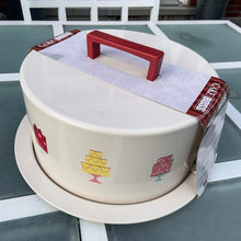 Load image into Gallery viewer, Add some playful vintage style to your kitchen decor with this Cake Boss brand metal cake carrier featuring a series of colorful cake graphics on a beige background with red handle. This handy carrier has 2 locking mechanisms to keep your cake safe during storage and make transporting your creation super easy!  New old stock in original packaging, never opened. In excellent condition. Crafted in China.  Overall measures 13 1/4 x 7 1/4 inches and fits a cake up to 10 1/2 x 5 inches
