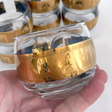 Load image into Gallery viewer, Fabulous vintage mid-century modern Carousel punch bowl with ten matching roly poly glasses and gold toned metal ladle. The glassware is decorated with carousel horses and carriages in 22kt gold on teal blue paint. Crafted by Colony, USA, circa 1960s. Perfect for serving eggnog, alcohol or non-alcohol punch at your next soirée! Stunning doesn&#39;t quite describe this fabulous set which is sure to be a standout at your next party!
