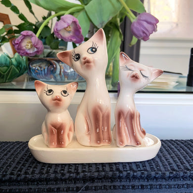 Get ready to spice up your kitchen with this oh-so-adorable cat family set of salt and pepper shakers — complete with a kitschy toothpick holder and stand! This vintage ceramic Taiwan set features a creamy white glaze with brown and black details. Purr-fect!  In excellent condition, free from chips/cracks.  Overall measures 5 3/4 x 2 x 6 inches