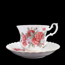 Load image into Gallery viewer, A lovely vintage Centennial Rose Monstrose shaped bone china teacup and saucer. Each piece has a lovely scalloped edge featuring a hand painted rose sprays with gold gilt trim. Crafted by Royal Albert, England, circa 1960s/70s. The perfect vessel for an excellent cuppa tea!

In excellent condition, no chips, cracks or repairs. Maker&#39;s marks on the bottom.

Teacup measures 3 1/2 x 2 3/4 inches | Saucer measures 5 1/2 inches
