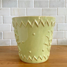 Load image into Gallery viewer, Rare vintage chartreuse green planter pot with embossed flower motif and zig zag borders. Crafted by McCoy Pottery, 1954. This rare planter is must for any McCoy art pottery collector. A wonderful piece to elevate your home and garden decor or to give as a gift!

In as found vintage condition, chip to the rim and crack, no repairs. Normal age-related crazing and manufacturer's glaze pops. Maker's mark on the bottom.

Measures 6 1/2 x 6 1/8 inches
