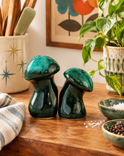 Load image into Gallery viewer, Canuck Pottery Evangeline green mushroom salt and pepper shakers on a wooden counter beside a plant and seasoning bowls

