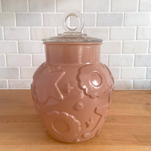 Load image into Gallery viewer, Vintage mid-century chocolate brown glass cookie jar with embossed gingerbread men, donuts, stars and cookies with clear ring handled lid. Crafted by Hazel-Atlas Glass, USA, 1950s. Use this nice sized jar to store cookies or dry goods and add whimsy to your kitchen decor.

In vintage condition with chips to the interior rim of the jar. The lid is in excellent condition, no chips.

Measures 6 1/2 x 10 inches
