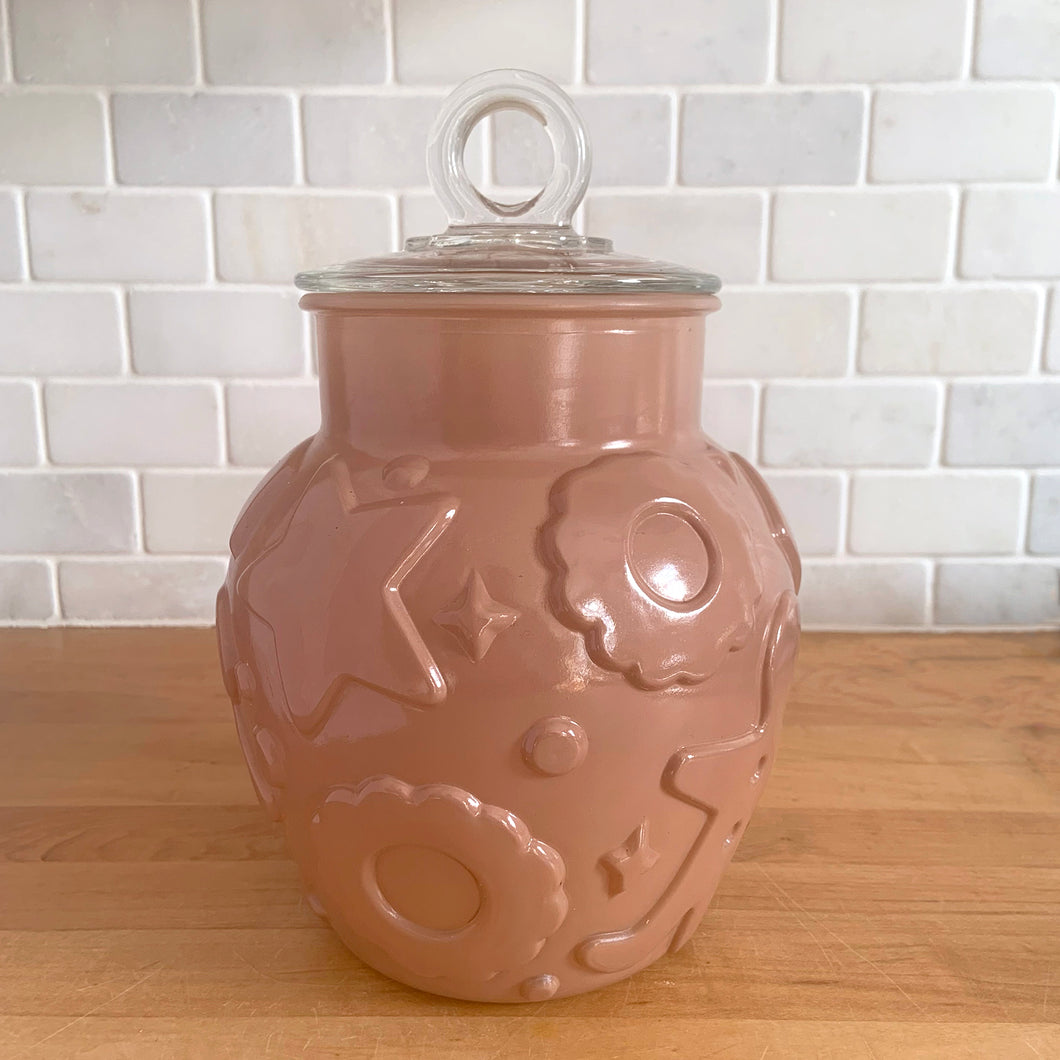 Vintage mid-century chocolate brown glass cookie jar with embossed gingerbread men, donuts, stars and cookies with clear ring handled lid. Crafted by Hazel-Atlas Glass, USA, 1950s. Use this nice sized jar to store cookies or dry goods and add whimsy to your kitchen decor.

In vintage condition with chips to the interior rim of the jar. The lid is in excellent condition, no chips.

Measures 6 1/2 x 10 inches