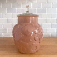 Load image into Gallery viewer, Vintage mid-century chocolate brown glass cookie jar with embossed gingerbread men, donuts, stars and cookies with clear ring handled lid. Crafted by Hazel-Atlas Glass, USA, 1950s. Use this nice sized jar to store cookies or dry goods and add whimsy to your kitchen decor.

In vintage condition with chips to the interior rim of the jar. The lid is in excellent condition, no chips.

Measures 6 1/2 x 10 inches
