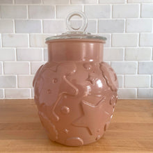 Load image into Gallery viewer, Vintage mid-century chocolate brown glass cookie jar with embossed gingerbread men, donuts, stars and cookies with clear ring handled lid. Crafted by Hazel-Atlas Glass, USA, 1950s. Use this nice sized jar to store cookies or dry goods and add whimsy to your kitchen decor.

In vintage condition with chips to the interior rim of the jar. The lid is in excellent condition, no chips.

Measures 6 1/2 x 10 inches
