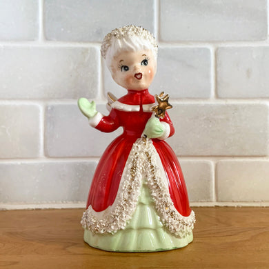 This sweet vintage hand painted ceramic Christmas angel bell holds a gold wand in one green-mittened hand while the other is waving. She is beautifully dressed in a red cloak trimmed in white spaghetti with gold details. Crafted for NAPCO in Japan, circa 1950s. A lovely piece of the past to add to your holiday present!  In excellent condition, free from chips/cracks/repairs, minor wear to the paint. Original clapper. Marked S1694A Japan.  Measures 2 3/4 x 2 x 5 1/4 inches