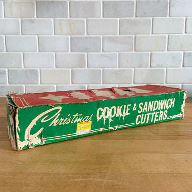 We love sharing vintage Christmas goods that bring back fond memories of baking for the holidays. This set of metal cookie and sandwich cutters has an attached handle for ease of use. Perfect for making Christmas memories with family! In good used vintage condition. In the original well-worn box.