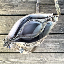 Load image into Gallery viewer, Pre-owned Ciana taupe faux python cross-body bag with adjustable strap is crafted from durable textured cow leather and features polished silver tone hardware. By Danier Leather. The zippered polyester lined interior has three compartments, one zippered pocket and metal keychain holder, one with snap closure, and one with 2-part open pocket. Exterior 2 zippered and snap closure pockets. A stylish, durable and practical accessory.
