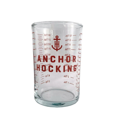 Clear glass measuring beaker displaying the Anchor Hocking logo and measures in red. Crafted by Anchor Hocking, USA. Helpful for small liquid measures.  In excellent condition, no chips.  Measures 2 x 2 1/4 inches  Capacity 5 ounces