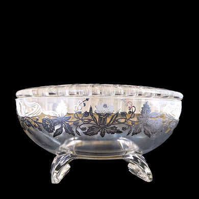 This exquisite vintage flowerlite features a clear oval or oblong shape adorned with a delicate silver overlay of orchid flowers. Crafted by Viking Art Glass in the 1950s, it includes a glass flower frog designed to hold two taper candles and rests on elegant Chinoiserie-style scrolled feet. Ideal for creating sophisticated floral arrangements, this Hollywood Regency piece enhances any space with timeless charm, whether illuminated by candlelight or displayed on its own in both modern and vintage interiors.