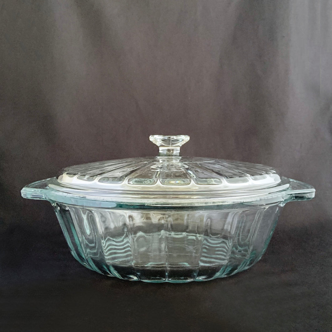 This large vintage clear glass lidded casserole dish has a distinctive scalloped design that makes cooking and serving effortless. It is oven, microwave, and dishwasher safe, making it easy to transport and reheat your favorite dishes with minimal mess. Crafted by Anchor Hocking, USA, circa 1950s, this dish is sure to bring style and convenience to your kitchen.  In excellent condition, free from chips.  Measures 9 inches / 23 cm  Capacity 2 quarts/litres