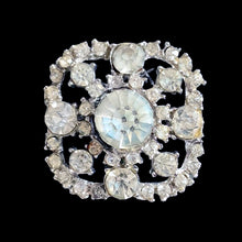 Load image into Gallery viewer, Front view of vintage clear rhinestone brooch showing large faceted centre stone and circular openwork silver-tone frame, square orientation
