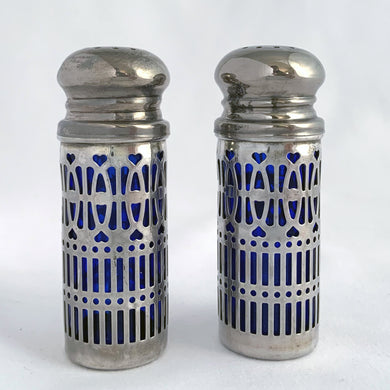 Vintage cobalt blue glass salt and pepper shakers featuring silver plate filigree sleeves. UK Patent 1014132, England. We've polished these and they will look lovely on any tablescape!  In good vintage condition, no chips to the glass. Wear to the lids, see photos.   Measures 7/8 x 2 3/4 inches