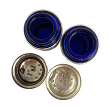 Load image into Gallery viewer, Vintage cobalt blue glass salt and pepper shakers featuring silver plate filigree sleeves. UK Patent 1014132, England. We&#39;ve polished these and they will look lovely on any tablescape!  In good vintage condition, no chips to the glass. Wear to the lids, see photos. Measures 7/8 x 2 3/4 inches
