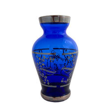 Load image into Gallery viewer, Vintage cobalt blue hand blown Murano art glass bud vase decorated with a Venetian scene and florals in silver overlay. Crafted in Italy, 1950s. A lovely piece of art glass from the mid-century, perfect for display and even sweeter with a bouquet of flowers.

In excellent condition, no chips.

Measures 2 1/2 x 2 1/2 x 4 3/4 inches
