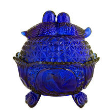 Load image into Gallery viewer, Large vintage cobalt blue love birds 3-footed, lidded candy dish, Byrdes reproduction. A licensed reproduction of the Hofbauer Byrdes model, 1990s. A gorgeous vessel to stash candy, keys, cotton balls and more!!!

In vintage condition with minor smooth chip to the outer rim and minor flea bites to both pieces which do not detract from the beauty of this piece thanks to the deep colour of the glass which tends to hide small issues.

Measures 7 1/2 x 7 1/2 inches
