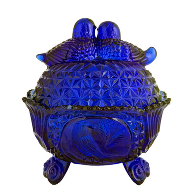 Large vintage cobalt blue love birds 3-footed, lidded candy dish, Byrdes reproduction. A licensed reproduction of the Hofbauer Byrdes model, 1990s. A gorgeous vessel to stash candy, keys, cotton balls and more!!!

In vintage condition with minor smooth chip to the outer rim and minor flea bites to both pieces which do not detract from the beauty of this piece thanks to the deep colour of the glass which tends to hide small issues.

Measures 7 1/2 x 7 1/2 inches