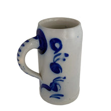 Load image into Gallery viewer, Vintage 1L German salt-glazed stoneware beer stein tilted at an angle, showing cobalt blue hand-painted cursive script and striped handle detail, grey ceramic body
