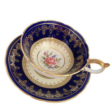 Vintage Bone China teacup and saucer with scalloped edge features a hand painted cobalt blue and pale yellow banded interior on a white ground, lavishly decorated with gold gilt filigree, complemented by pink cabbage roses at the bottom of the cup and centre of the saucer. Aynsley, England. 1930s.  In excellent condition. Maker's mark with decorator's hand painted C553 Teacup measures 4 x 2 1/4 inches Saucer measures 5 5/8 inches