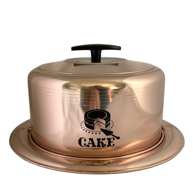 Vintage copper/rose gold toned aluminum dome cake carrier keeper featuring a black bakelite handle and an illustration in black of a sliced cake with the word 