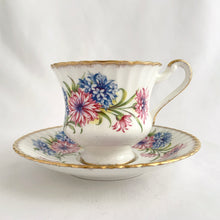 Load image into Gallery viewer, Stunning vintage white porcelain teacup and matching saucer featuring pink cornflowers and blue flowers plus gold gilt details with a spray of flowers on the interior of the teacup. Produced by The Paragon China Company, England, circa 1950s.  In excellent condition, free from chips/cracks/repairs. Marked on the bottom with single warrant stamp.  Teacup measures 3 1/8 x 2 3/4 inches  Saucer measures 5 3/8 inches
