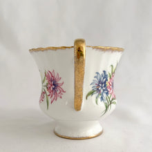 Load image into Gallery viewer, Stunning vintage white porcelain teacup and matching saucer featuring pink cornflowers and blue flowers plus gold gilt details with a spray of flowers on the interior of the teacup. Produced by The Paragon China Company, England, circa 1950s.  In excellent condition, free from chips/cracks/repairs. Marked on the bottom with single warrant stamp.  Teacup measures 3 1/8 x 2 3/4 inches  Saucer measures 5 3/8 inches
