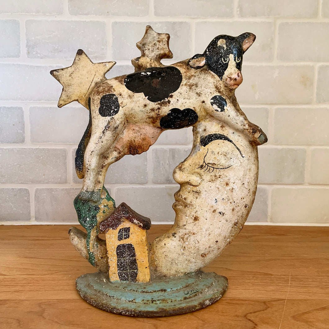Rare early 20th century vintage The Cow Jumped Over the Moon nursery rhyme hand painted cast iron doorstop. Signed by the artist Arni on the base. This solid, one-piece diecast cut doorstop is an original free of mold seams, screws or grind marks and weighs 4 1/4 pounds. A wonderful piece of folk art to add charm to your home's decor.

In as found vintage condition with wear to the paint and rusty patina.

Measures 7 x 8 1/2 inches