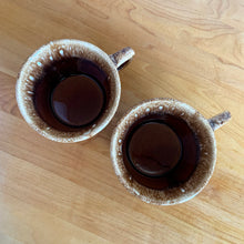 Load image into Gallery viewer, Pair of vintage Crestone glossy brown drip glaze mugs with flare rim. Crafted by Hull Pottery, USA, 1960s. Enjoy any hot beverage in this fabulous retro oven-proof tableware!

In excellent condition, no chips/cracks/repairs. Maker&#39;s marks.

Measures 4 x 2 3/4 inches

Capacity 8 ounces
