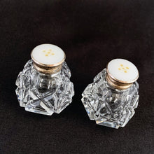 Load image into Gallery viewer, A pair of traditional vintage round paneled shaped cut crystal salt and pepper shakers in the art deco style featuring an &quot;X&quot; and diamond pattern with sterling silver mother-of-pearl lids.   In excellent condition, no chips or cracks. Marked 925 Sterling.  Measures 1 1/2 x 1 3/4 inches   
