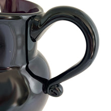 Load image into Gallery viewer, Vintage deep purple hand blown glass pitcher with applied curled handle and smooth pontil. Maker unknown. A stunning and versatile pitcher that may be used to serve your favourite beverage, serve as a flower vase or artisanal glass decor.

In excellent used condition, no chips, minor wear.

Measures 7 x 5 x 10 (incl handle/spout)
