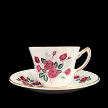 Load image into Gallery viewer, Vintage fine bone china teacup and saucer featuring dark pink roses, pale blue baby&#39;s breath and gold gilt trim on a swirl shape. Crafted by Delphine, England, 1930 - 1941. A lovely way to enjoy a cuppa tea!

In excellent condition, no chips, cracks or repairs. Maker&#39;s mark on the bottom.

Measures 3 3/8 x 2 1/2 inches | Saucer measures 5 3/4 inches
