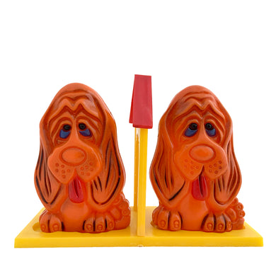 Vintage plastic rusty-orange Basset hound dog salt and pepper shaker with yellow and red dog house tray, plastic stoppers. JSNY, Hong Hong 1970s. Add these adorable shakers to your collection!

In excellent vintage condition. Maker's mark on dogs and tray bottom .

Dog measures 1 3/4 x 1 1/2 x 3 inches, tray measures 4 5/8 x 2 x 3 3/8 inches