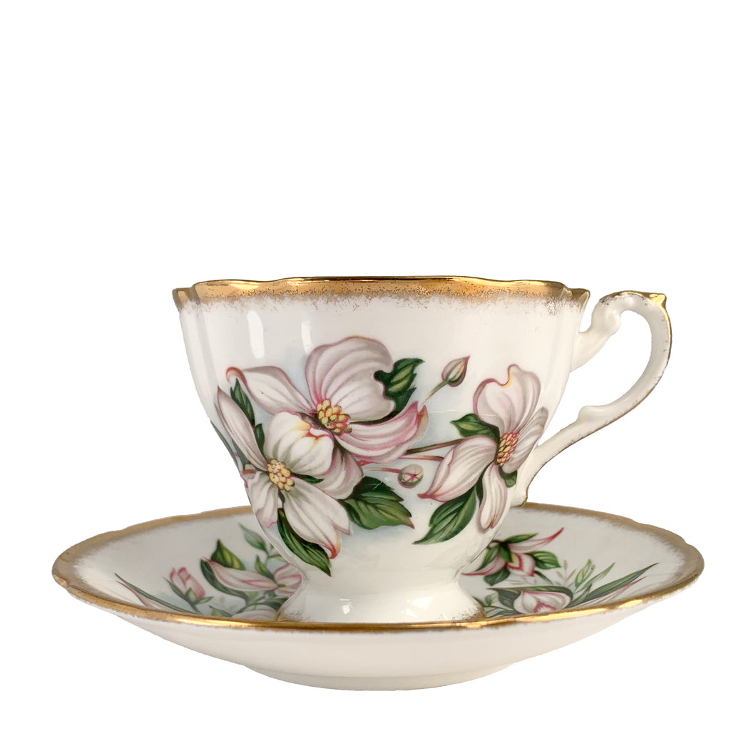 Vintage Dogwood fine bone china teacup and saucer featuring hand painted flowers in shades of pink, gray and green with brush gold gilt trim. Crafted by Paragon, England, 1960s. A lovely way to enjoy a cuppa tea!

In excellent condition, no chips, cracks or repairs. Maker's mark on the bottom.

Measures 3 3/4 x 2 3/4 inches | Saucer measures 5 inches