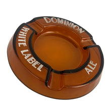 Load image into Gallery viewer, Vintage promotional advertising Dominion White Label Ale amber round glass ashtray. A great piece for the tobacciana and barware collector.  In vintage condition, minor flea bites to the interior rim and wear to the printing.  Measures 6 1/4 x 7/8 inches
