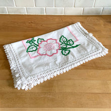 Load image into Gallery viewer, A lovely vintage white cotton dresser scarf or table runner, featuring a sweet hand embroidered pink flowers and green leaves with a pink inner border and beautifully crocheted edge. A gorgeous addition to your linen collection! In good used vintage condition, free from tears, minor stain.  Measures 34 1/2 x 15 inches
