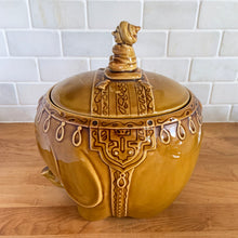 Load image into Gallery viewer, vintage cookie jar of figural elephant features a turbin wearing gentleman sitting on a pillow riding on top which forms the lid&#39;s finial. adorable and the expression on the rider&#39;s face is sassy! The elephant is beautifully decorated in an East Indian motif. Crafted by Noritake, Japan for Giftcraft export. In outstanding condition, free from chips/cracks/wear. We believe this is new old stock. Original sticker present and the bottom has the stamped maker&#39;s mark. Measures 7 1/2 x 5 1/2 x 9 3/4 inches
