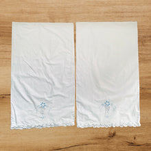 Load image into Gallery viewer, A lovely pair of vintage white cotton pillowcases, featuring elegantly design of hand embroidered flowers in pale blue, white details, cutwork and finished with scalloped edge in Battenburg Lace. A gorgeous addition to your bed linens! In excellent condition, free from tears or stains. Measures 32 3/4 x 19 13/4 inches
